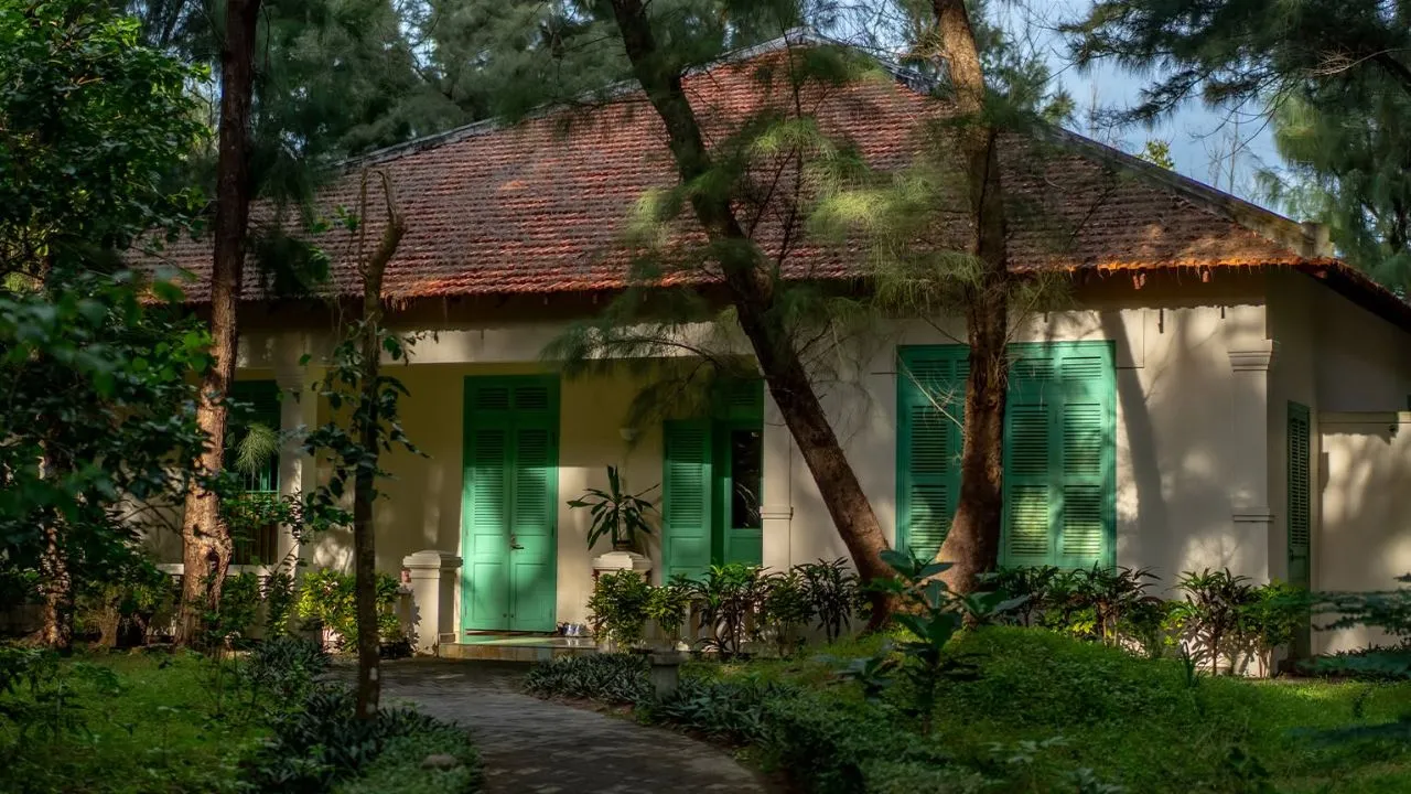 Hồ bơi ngoài trời Poulo Condor phản chiếu dãy villa mái ngói đỏ kiểu Pháp và núi xanh phía sau