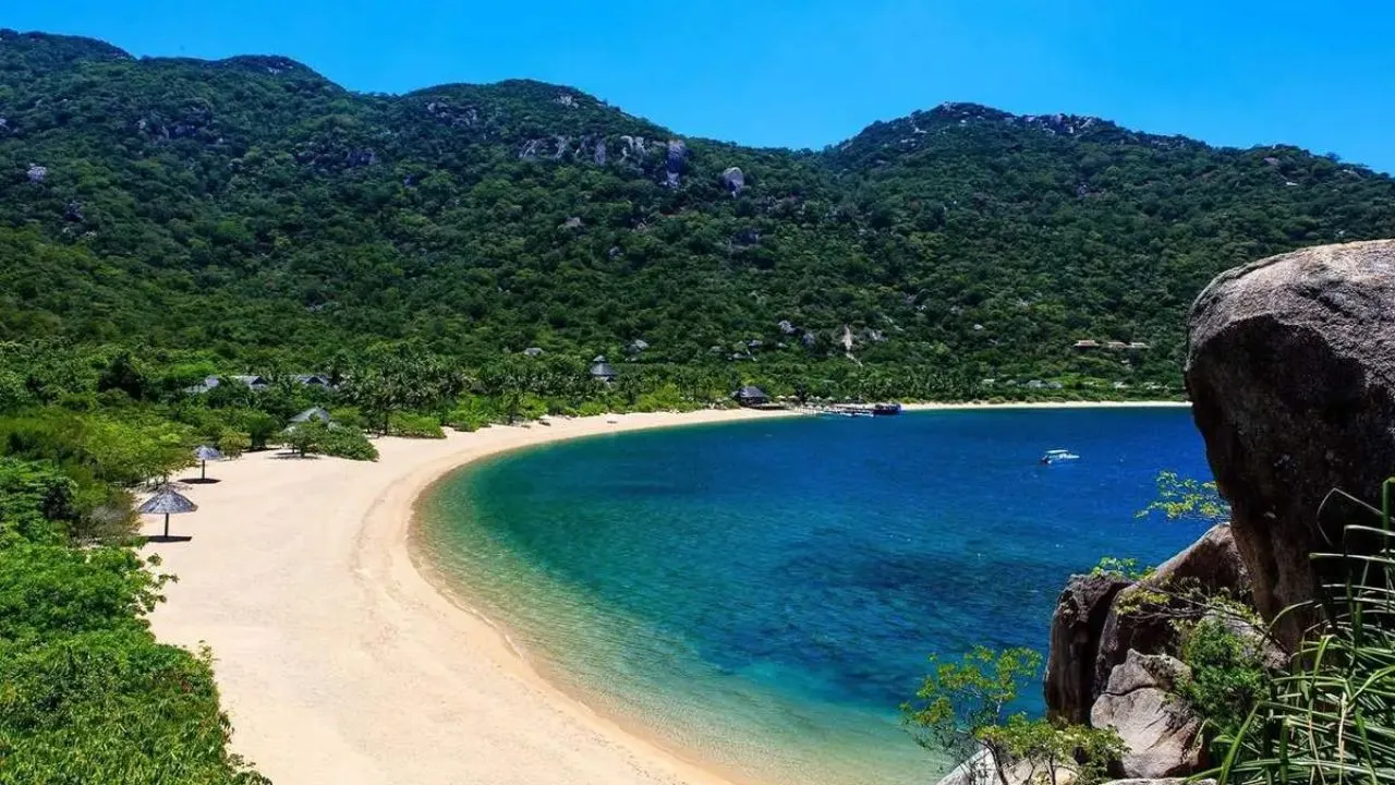 Bãi Đầm Trầu mặt nước lăn tăn, bờ cát vàng cong hình cánh cung, rừng xanh phía sau