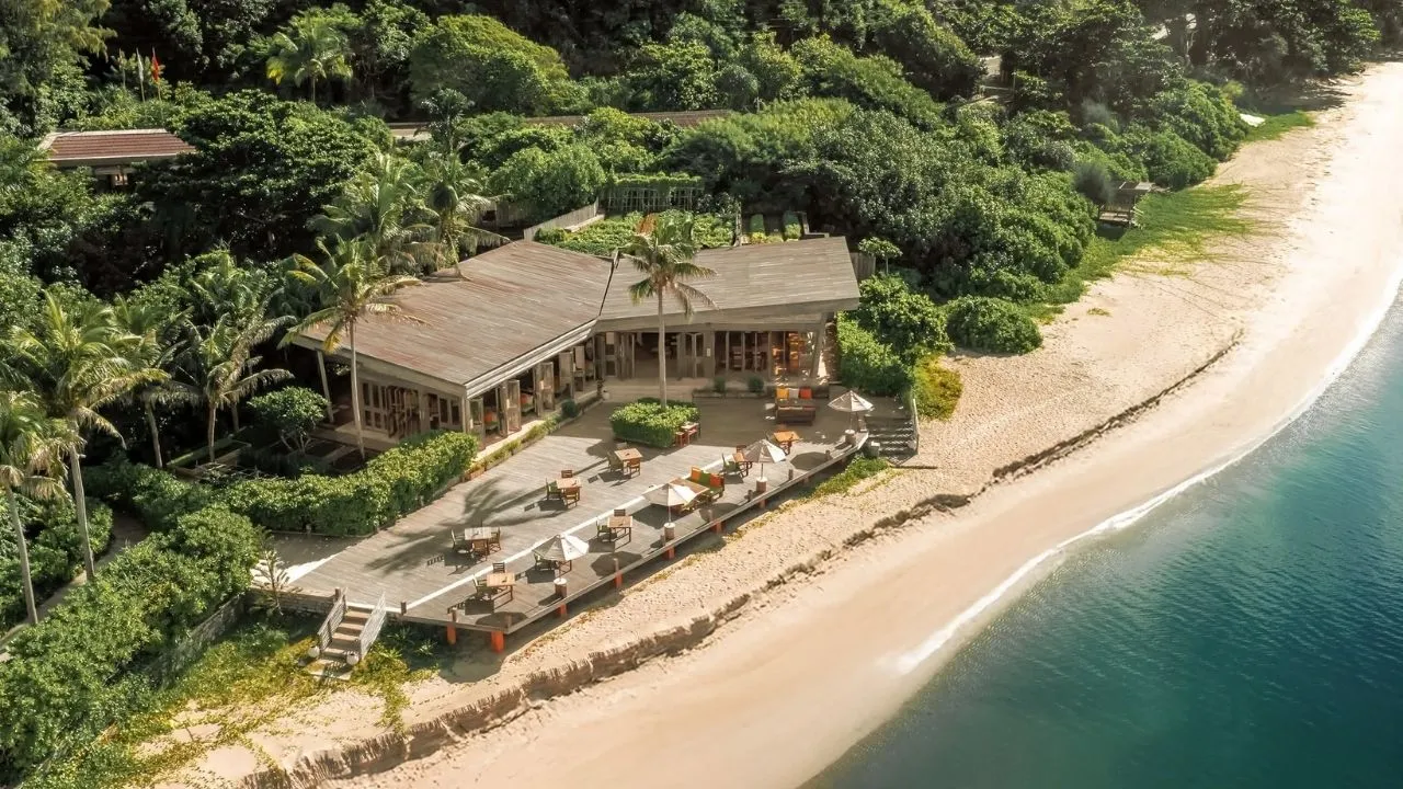 Dãy villa gỗ Six Senses Côn Đảo dọc đường cong Bãi Đất Dốc, mỗi villa có hồ bơi riêng trước hiên, phía sau là núi rừng xanh
